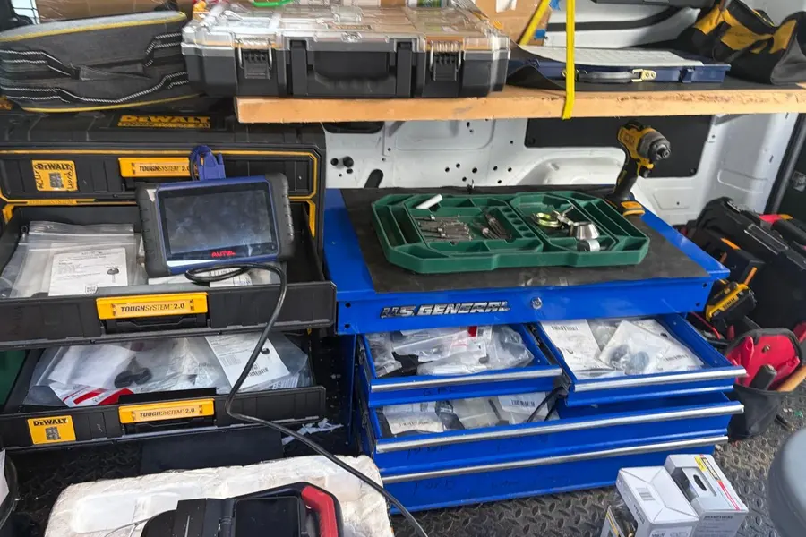 Autel key programming tablet on a tool chest full of key blanks and parts in the van
