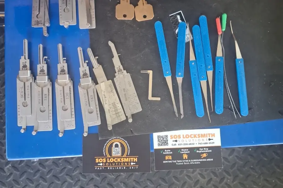 Lock pick set and Lishi 2-in-1 picks laid out next to an SOS business card