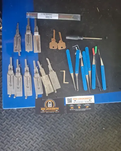 Lock pick set and Lishi 2-in-1 picks laid out next to an SOS business card
